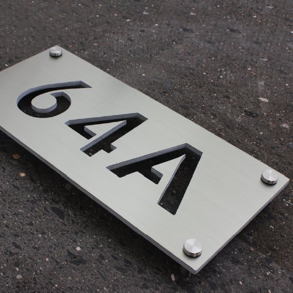 Números oficiales modernos en placa flotada, con los números huecos tipo esténcil.